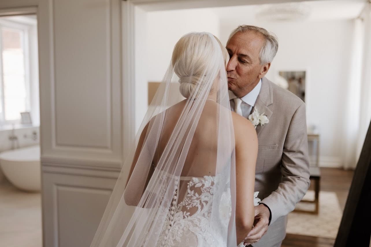 Bride greeting her father with a soft bridal updo under a veil